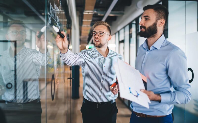 two men looking at whiteboard